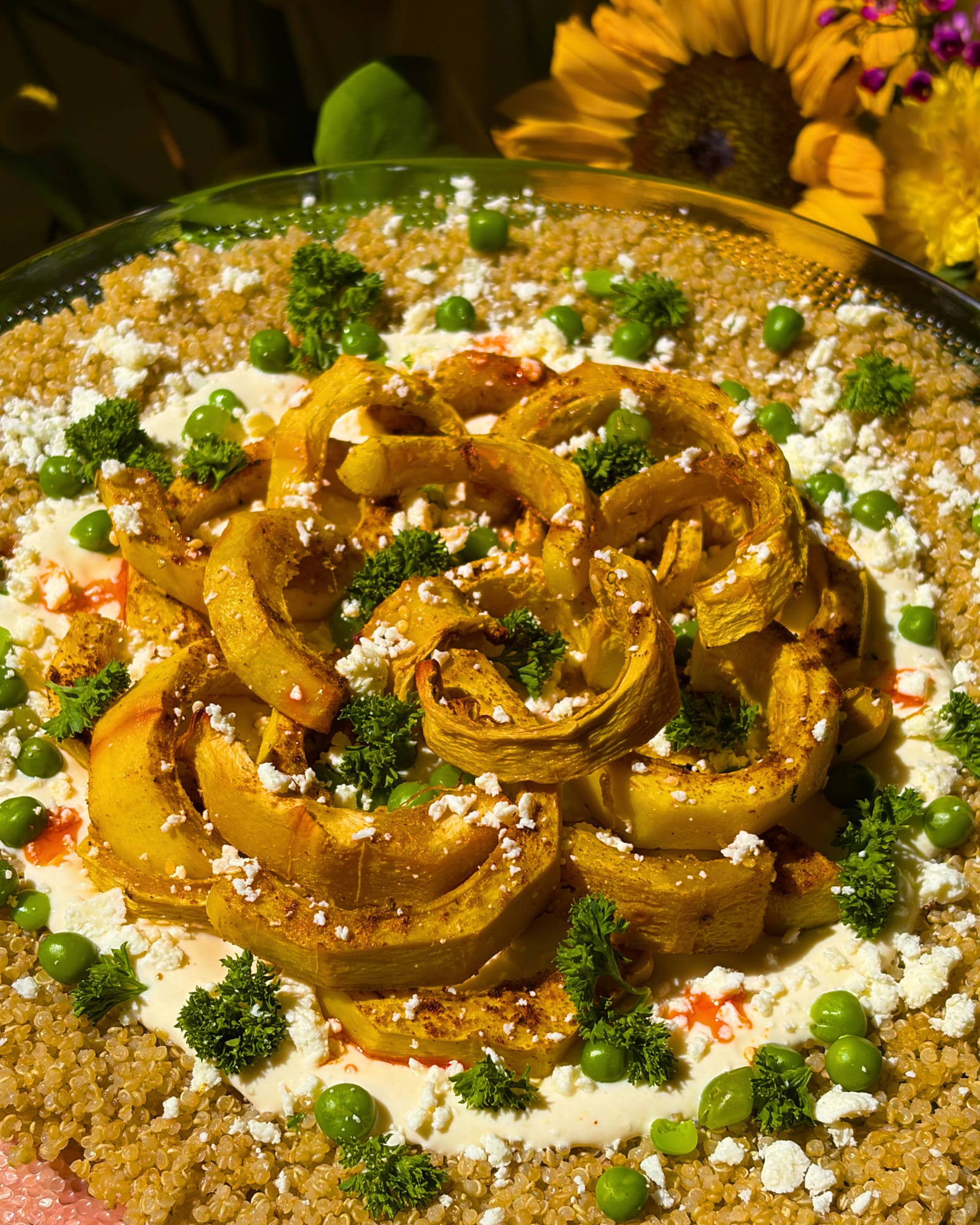 Hands seasoning a dish in a pan over a flame, surrounded by fresh vegetables and herbs